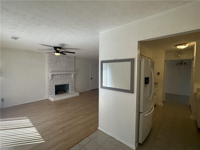 kitchen featuring a fireplace, a textured ceiling, ceiling fan, light hardwood / wood-style flooring, and white fridge with ice dispenser