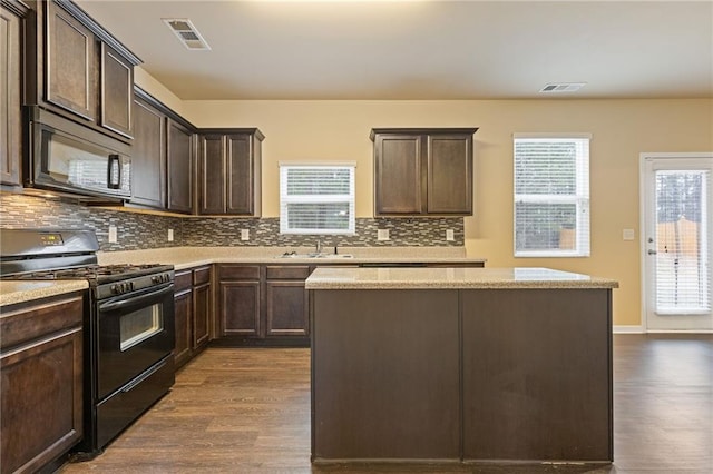 kitchen with dark wood-type flooring, black appliances, dark brown cabinets, and a kitchen island