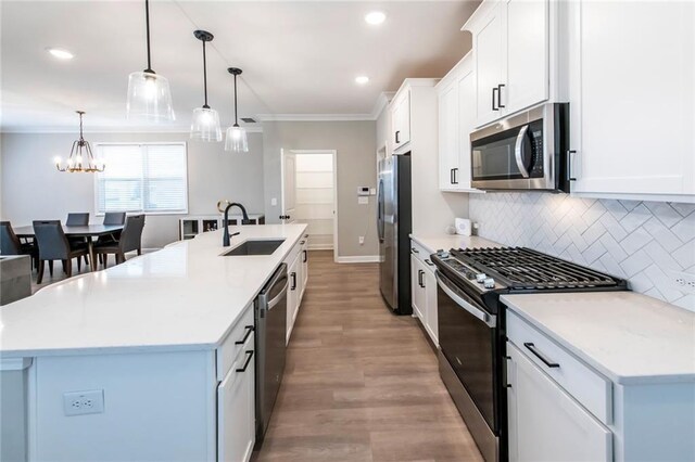 3739 Silvery Way, Powder Springs, GA 30127 - kitchen featuring an island with sink, a sink, stainless steel appliances, crown molding, and decorative backsplash