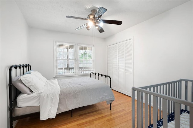 bedroom with a ceiling fan, a closet, a textured ceiling, and wood finished floors