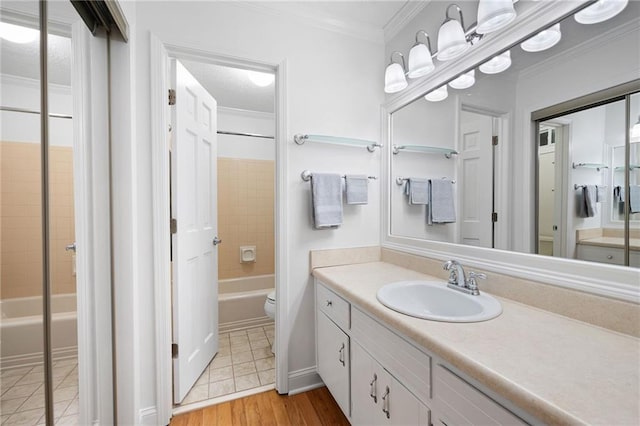 bathroom with toilet, wood finished floors, vanity, ornamental molding, and shower / bathing tub combination