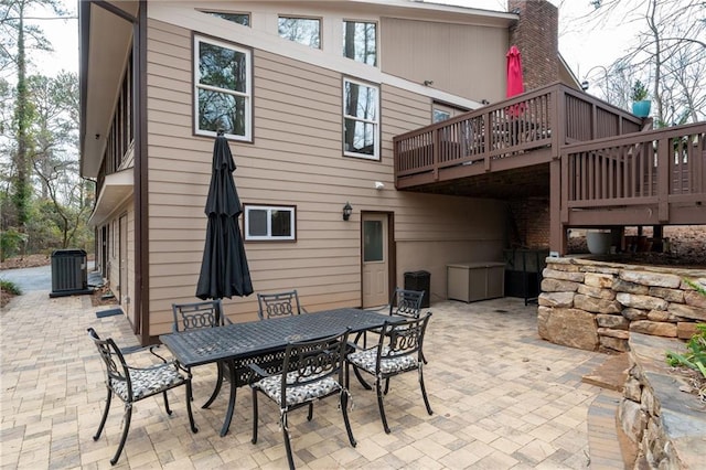 view of patio / terrace with outdoor dining area, a wooden deck, and central air condition unit