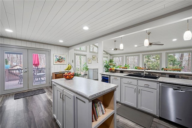 kitchen with plenty of natural light, vaulted ceiling, light countertops, stainless steel dishwasher, and a sink