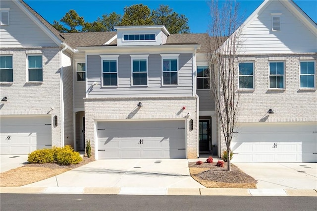 view of property featuring driveway, brick siding, and an attached garage