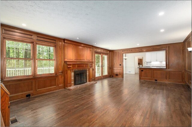 6141 Windsong Way, Smoke Rise, GA 30087 - unfurnished living room featuring dark wood-type flooring, a decorative wall, a brick fireplace, wooden walls, and a textured ceiling