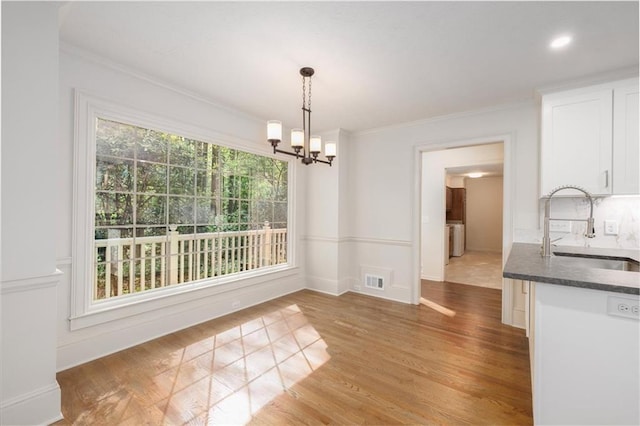6141 Windsong Way, Smoke Rise, GA 30087 - unfurnished dining area with a sink, ornamental molding, a chandelier, light wood-style floors, and baseboards