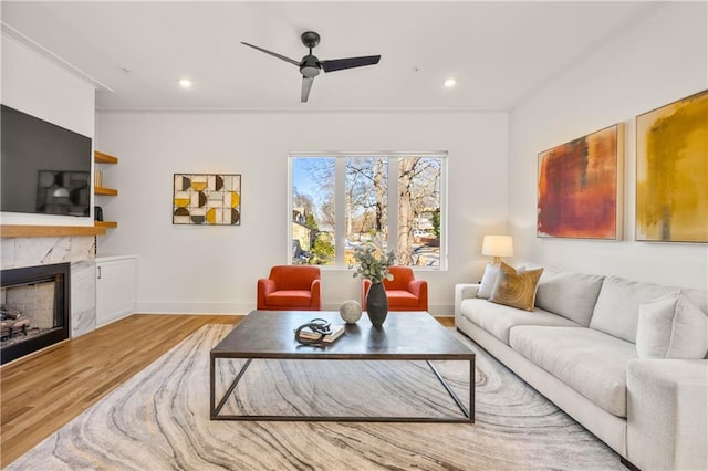 living area featuring light wood-type flooring, a fireplace, a ceiling fan, and recessed lighting