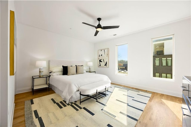 bedroom with baseboards, visible vents, ceiling fan, and light wood finished floors