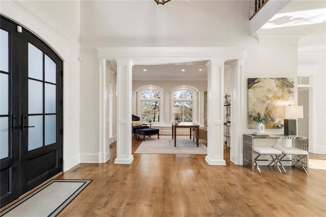 foyer with wood finished floors, decorative columns, french doors, and arched walkways