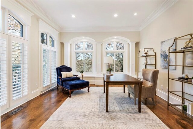 home office with wood finished floors, visible vents, baseboards, decorative columns, and crown molding