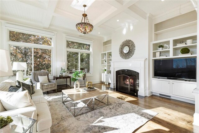 living room with beam ceiling, coffered ceiling, ornate columns, and wood finished floors