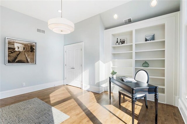 interior space featuring visible vents, lofted ceiling, baseboards, and wood finished floors