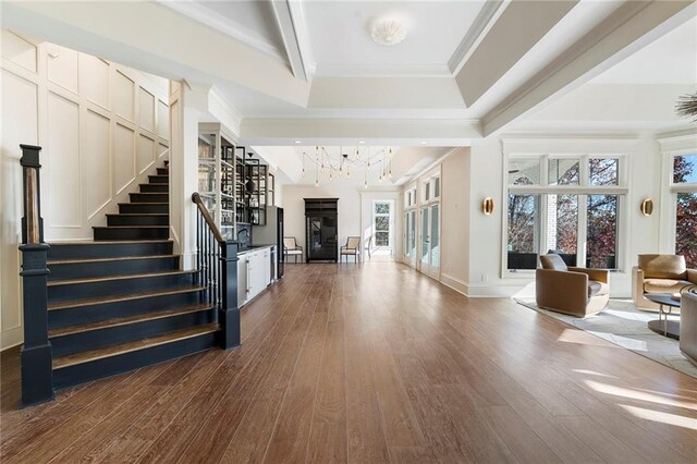 living area with stairway, built in features, beam ceiling, wood finished floors, and coffered ceiling