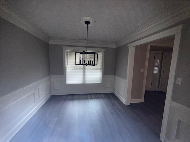 unfurnished dining area with dark wood finished floors, a wainscoted wall, a chandelier, and crown molding