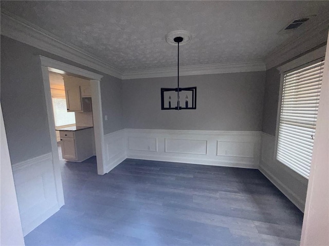 unfurnished dining area with visible vents, dark wood-type flooring, ornamental molding, wainscoting, and a healthy amount of sunlight