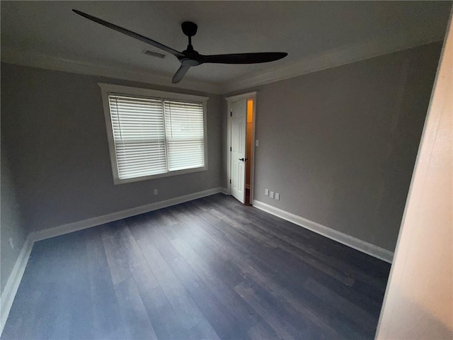 empty room featuring dark wood-style floors, ceiling fan, baseboards, and ornamental molding