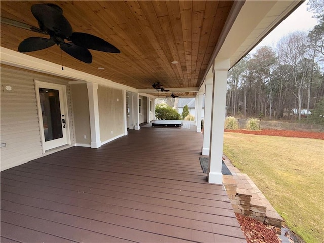 wooden terrace featuring a lawn, a porch, and ceiling fan