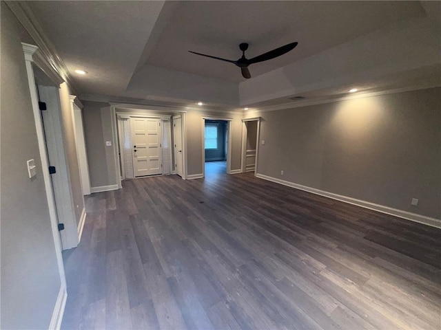 unfurnished bedroom with baseboards, a raised ceiling, ornamental molding, and dark wood-style flooring