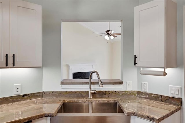 5410 Lenox Park Pl, Buford, GA 30518 - kitchen with a sink, stone counters, a fireplace, ceiling fan, and white cabinetry