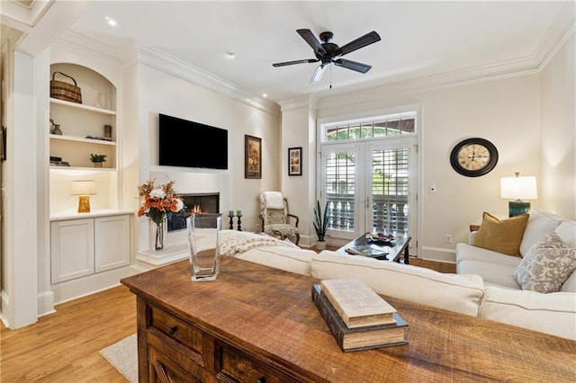 77 Peachtree Pl NE Unit 101, Atlanta, GA 30309 - living room featuring light wood-type flooring, a lit fireplace, crown molding, a ceiling fan, and built in features