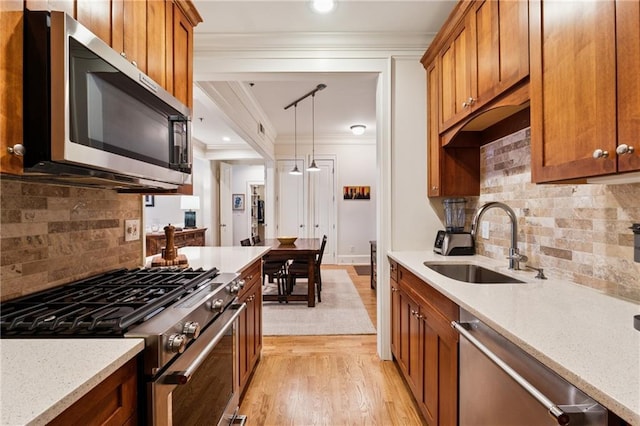 77 Peachtree Pl NE Unit 101, Atlanta, GA 30309 - kitchen with stainless steel appliances, crown molding, brown cabinetry, light wood finished floors, and tasteful backsplash