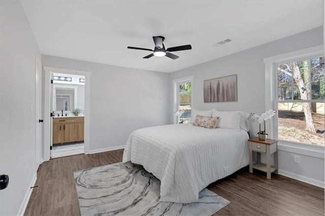 bedroom with dark wood-type flooring, ceiling fan, and connected bathroom