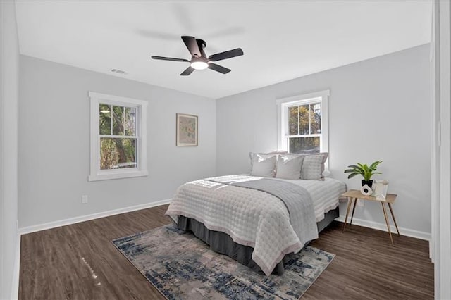 bedroom featuring dark wood-type flooring, ceiling fan, and multiple windows