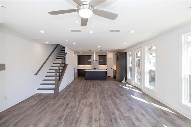 unfurnished living room with plenty of natural light, stairs, and wood finished floors