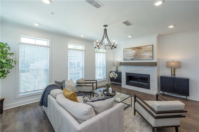 living room featuring a stone fireplace, wood finished floors, visible vents, baseboards, and crown molding