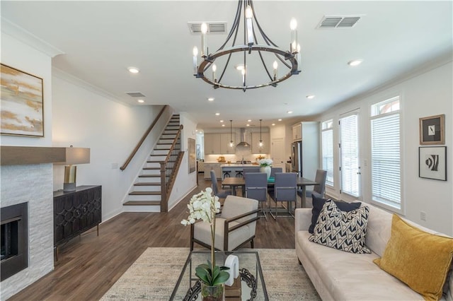 living room with dark wood-style floors, visible vents, crown molding, and a stone fireplace