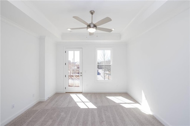 spare room with baseboards, carpet flooring, ceiling fan, and a tray ceiling