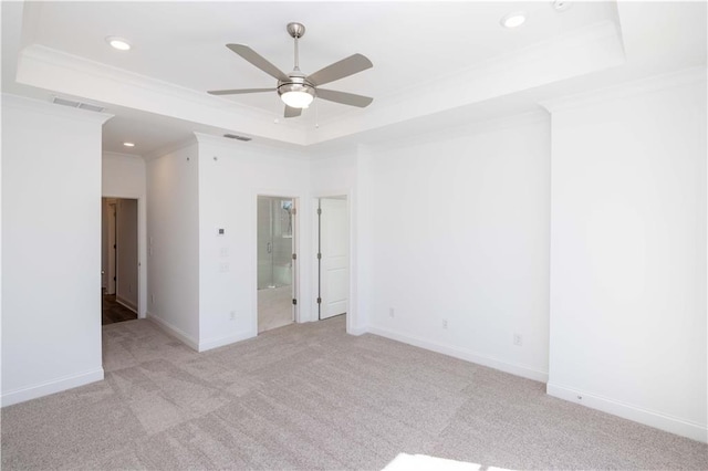 empty room with visible vents, ornamental molding, carpet floors, a tray ceiling, and a ceiling fan
