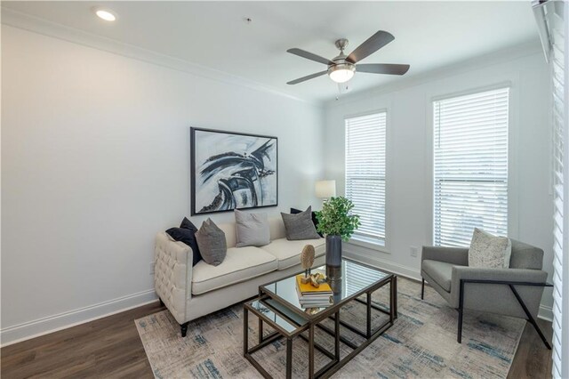 living room with ornamental molding, wood finished floors, a ceiling fan, and baseboards