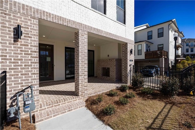 view of exterior entry with brick siding and fence
