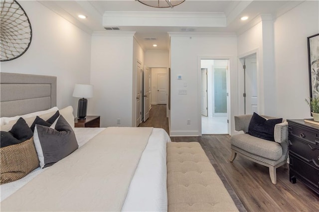 bedroom with visible vents, a raised ceiling, ornamental molding, wood finished floors, and recessed lighting