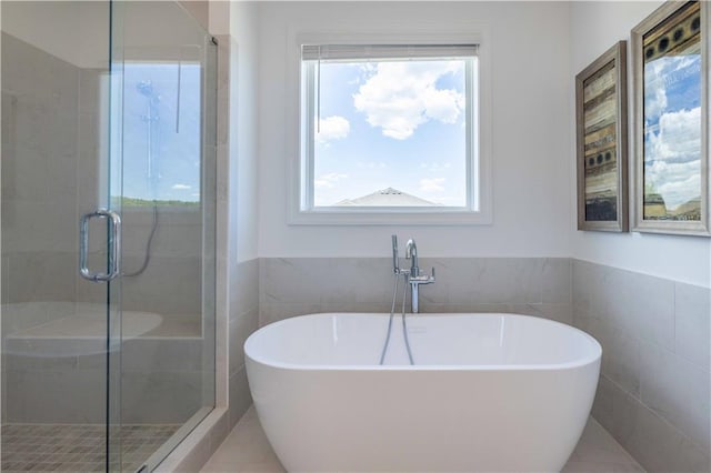 full bath with a soaking tub, a shower stall, tile walls, and wainscoting