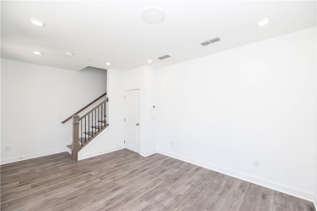 spare room with stairway, recessed lighting, wood finished floors, and visible vents