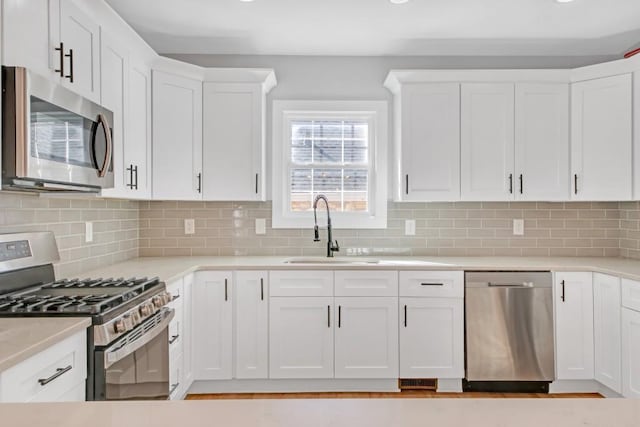 kitchen featuring sink, white cabinets, stainless steel appliances, and backsplash