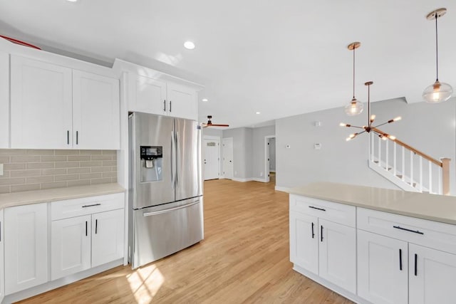 kitchen featuring decorative backsplash, hanging light fixtures, white cabinetry, light hardwood / wood-style flooring, and stainless steel refrigerator with ice dispenser