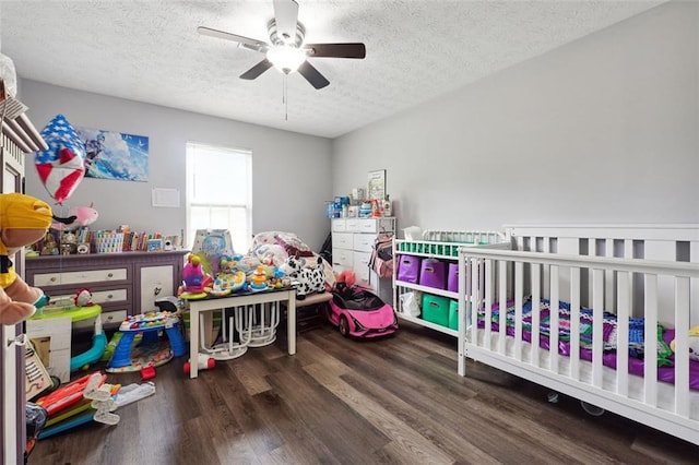 bedroom with ceiling fan, a crib, a textured ceiling, and hardwood / wood-style flooring