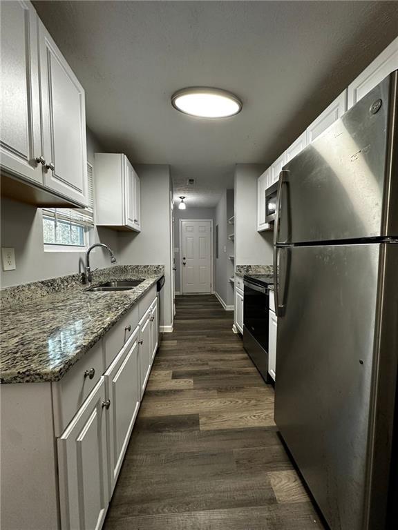 kitchen featuring white cabinets, dark hardwood / wood-style flooring, stainless steel appliances, sink, and light stone counters