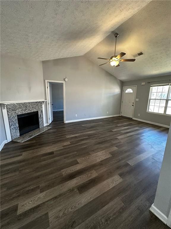 unfurnished living room with a textured ceiling, lofted ceiling, dark wood-type flooring, a fireplace, and ceiling fan