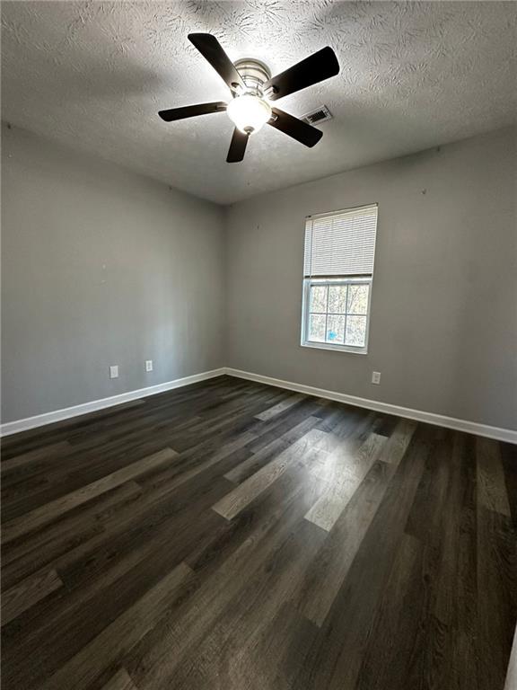 spare room with a textured ceiling, ceiling fan, and dark hardwood / wood-style flooring