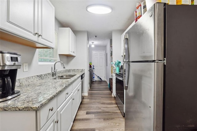 kitchen featuring hardwood / wood-style floors, sink, light stone countertops, stainless steel appliances, and white cabinets