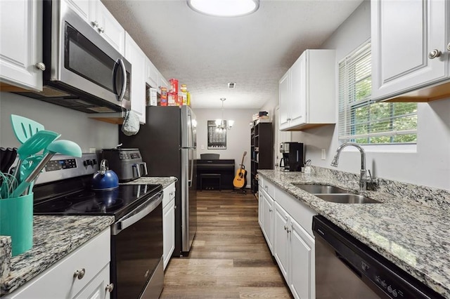 kitchen with appliances with stainless steel finishes, sink, white cabinetry, and pendant lighting