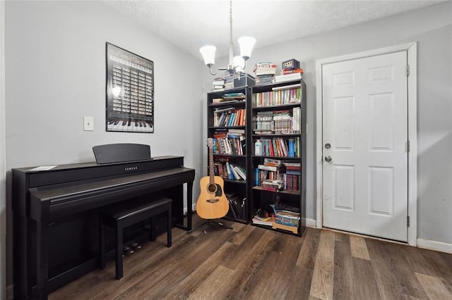 miscellaneous room featuring dark wood-type flooring, a textured ceiling, and a chandelier