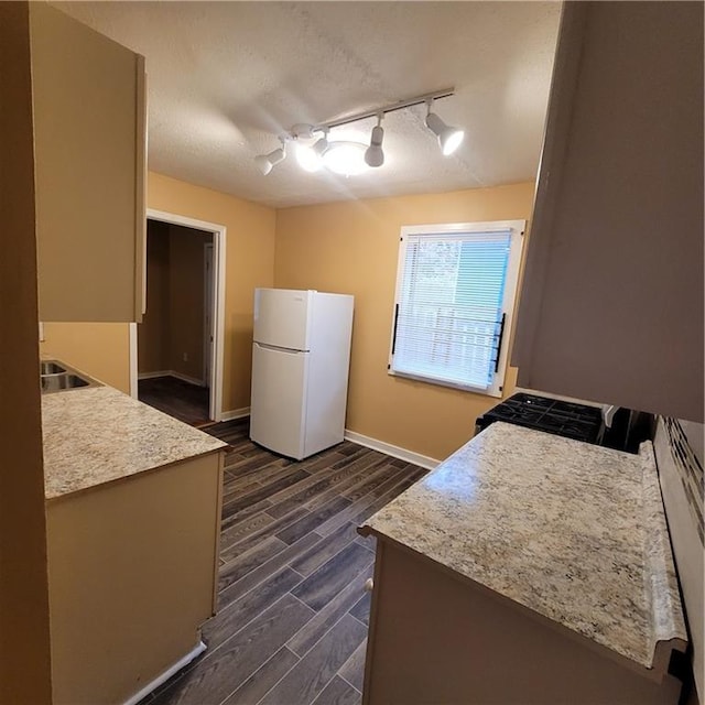 kitchen with baseboards, wood finish floors, light countertops, freestanding refrigerator, and a textured ceiling