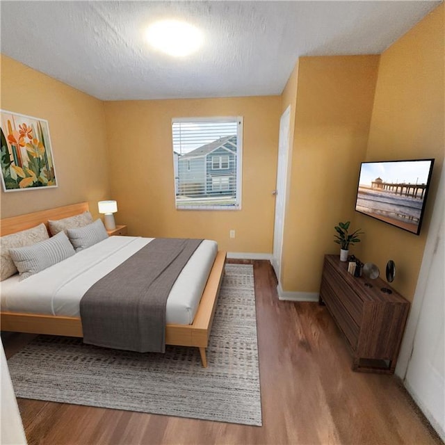 bedroom featuring wood finished floors, baseboards, and a textured ceiling