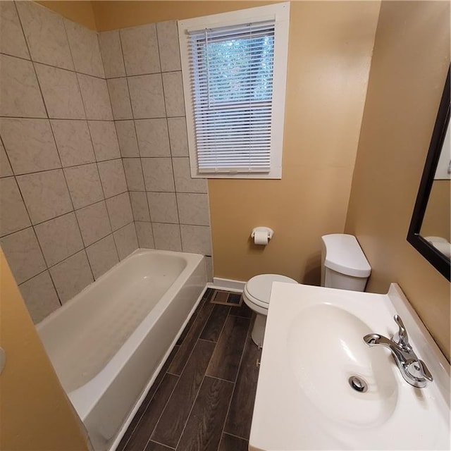 bathroom featuring baseboards, toilet, wood tiled floor, and a sink