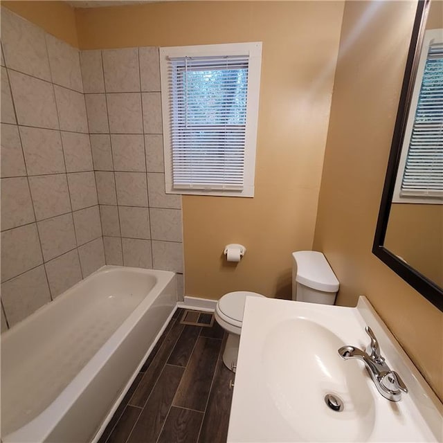 bathroom featuring wood finish floors, toilet, baseboards, and a sink